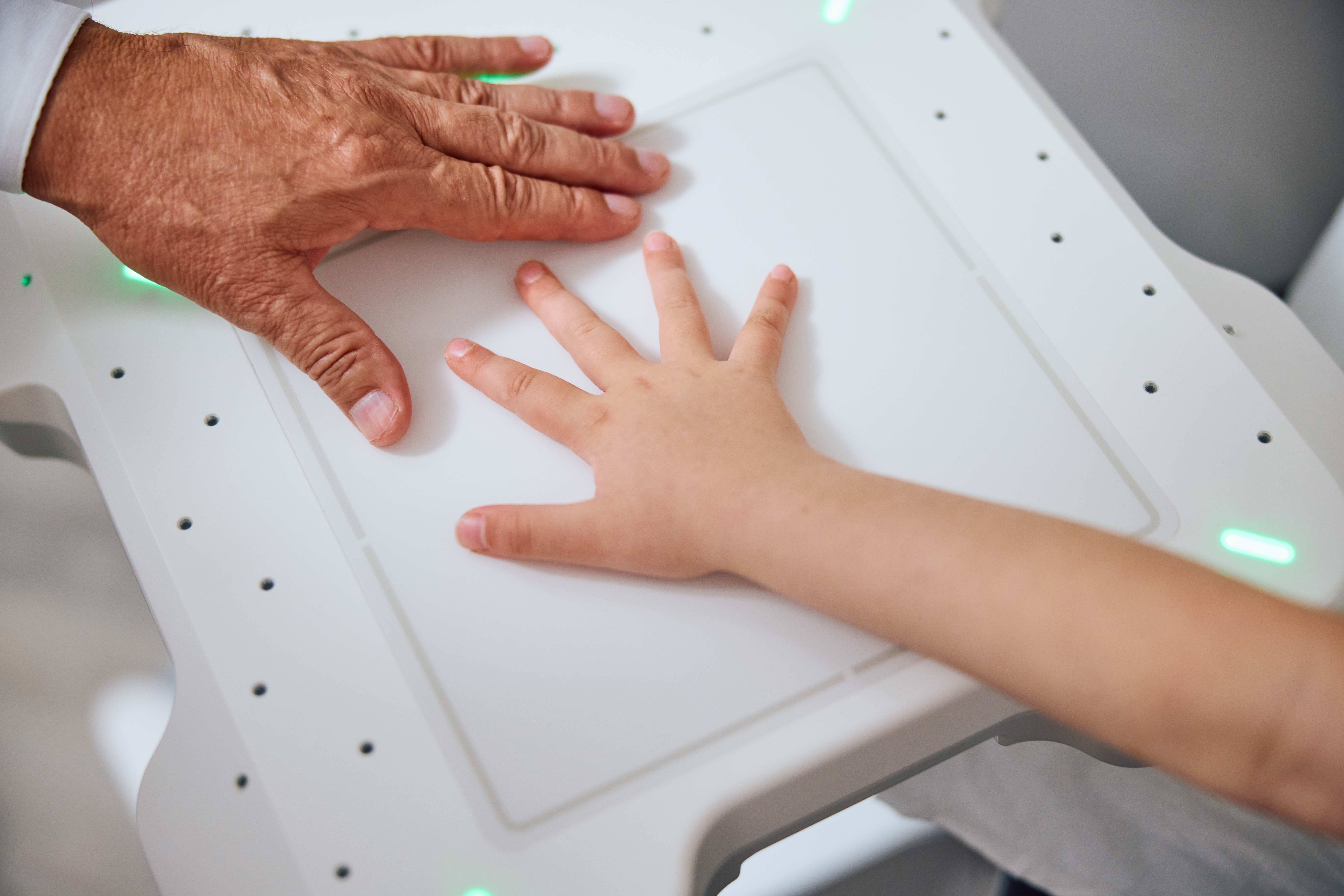 Pediatrician is positioning a childs hand on the X-ray detector.