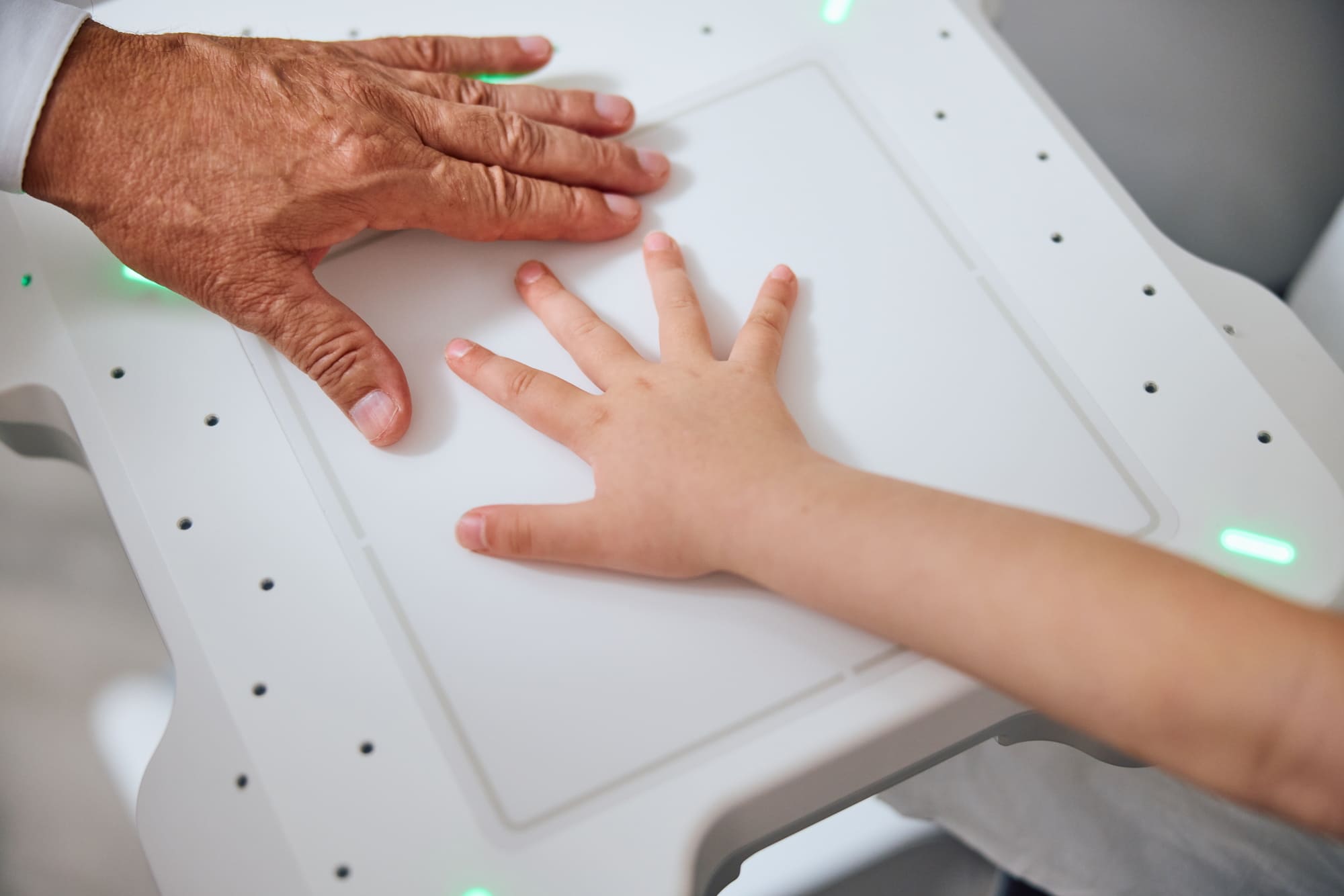 A small child has her hand postioned on the X-ray cassette before the pediatrician takes the image.